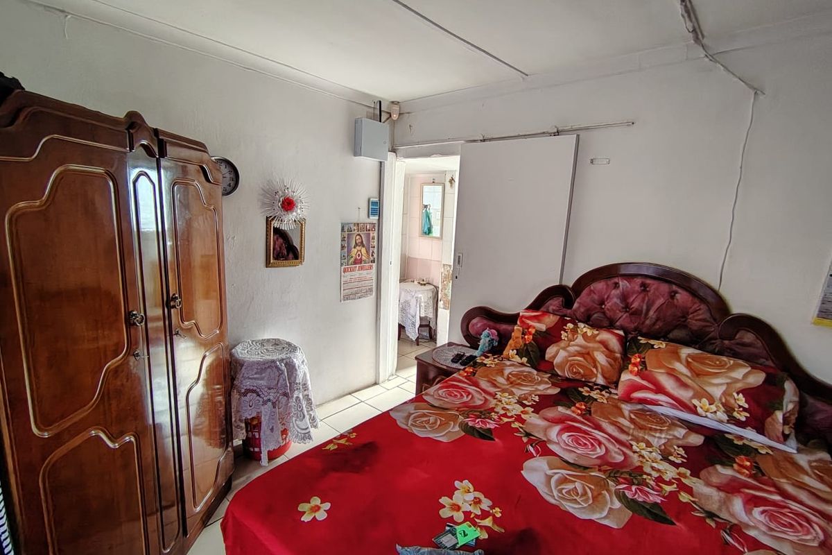 A bedroom featuring a sliding door and visible electrical distribution board, showing signs of wear on the ceiling and wall finishes.