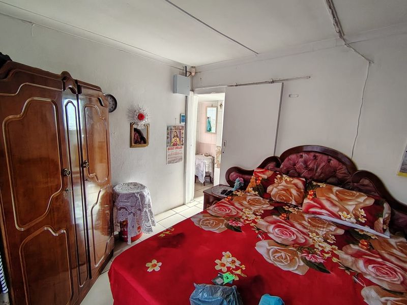 A bedroom featuring a sliding door and visible electrical distribution board, showing signs of wear on the ceiling and wall finishes.