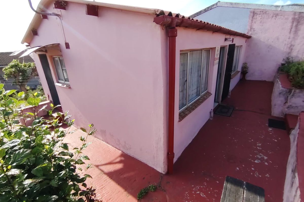 Rear exterior view of the property featuring a painted concrete patio, aluminium window frames, and a tiled roof structure.