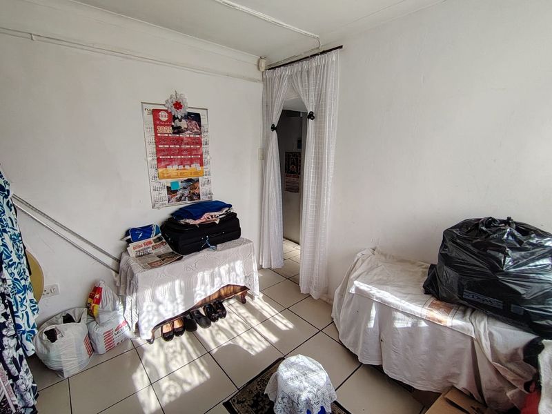 A bedroom featuring tiled flooring and basic wall finishes, currently used for storage.
