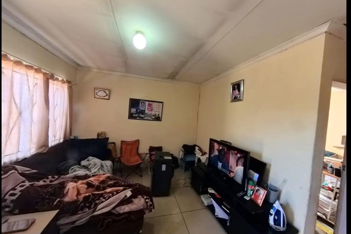A living room area featuring tiled flooring and a ceiling with visible wear and staining, offering a functional space for renovation.
