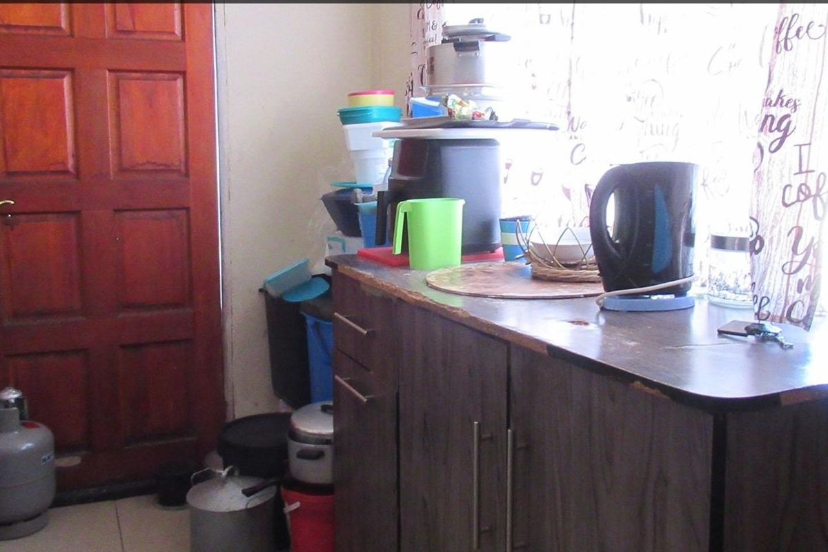 A small kitchen area featuring dark wood-look cabinetry and a laminate countertop, adjacent to a timber entrance door.