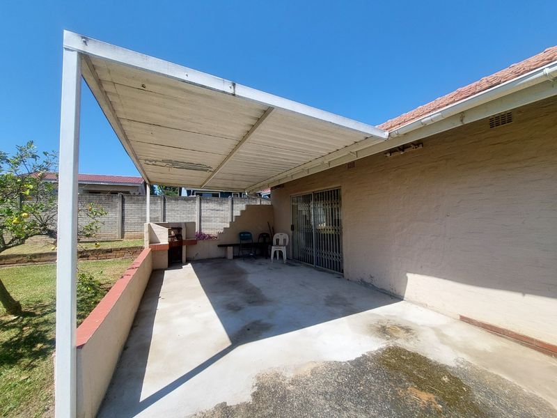 A covered outdoor patio area featuring a built-in braai, concrete flooring, and direct access to the home via a sliding security door.