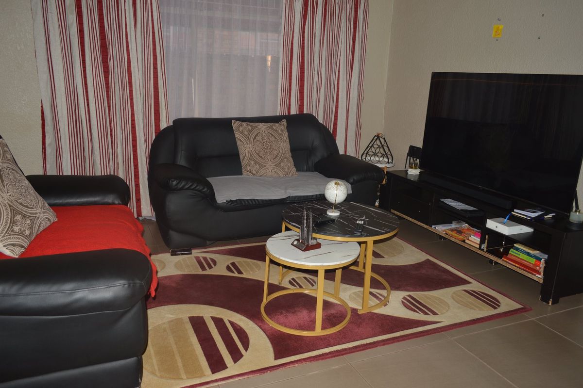 A living room area featuring tiled flooring and large window treatments.