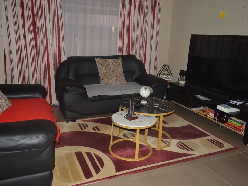 A living room area featuring tiled flooring and large window treatments.