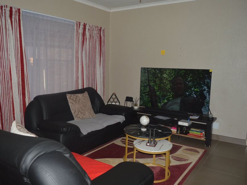 A standard living room featuring tiled flooring and neutral wall finishes, providing a functional space for relaxation.