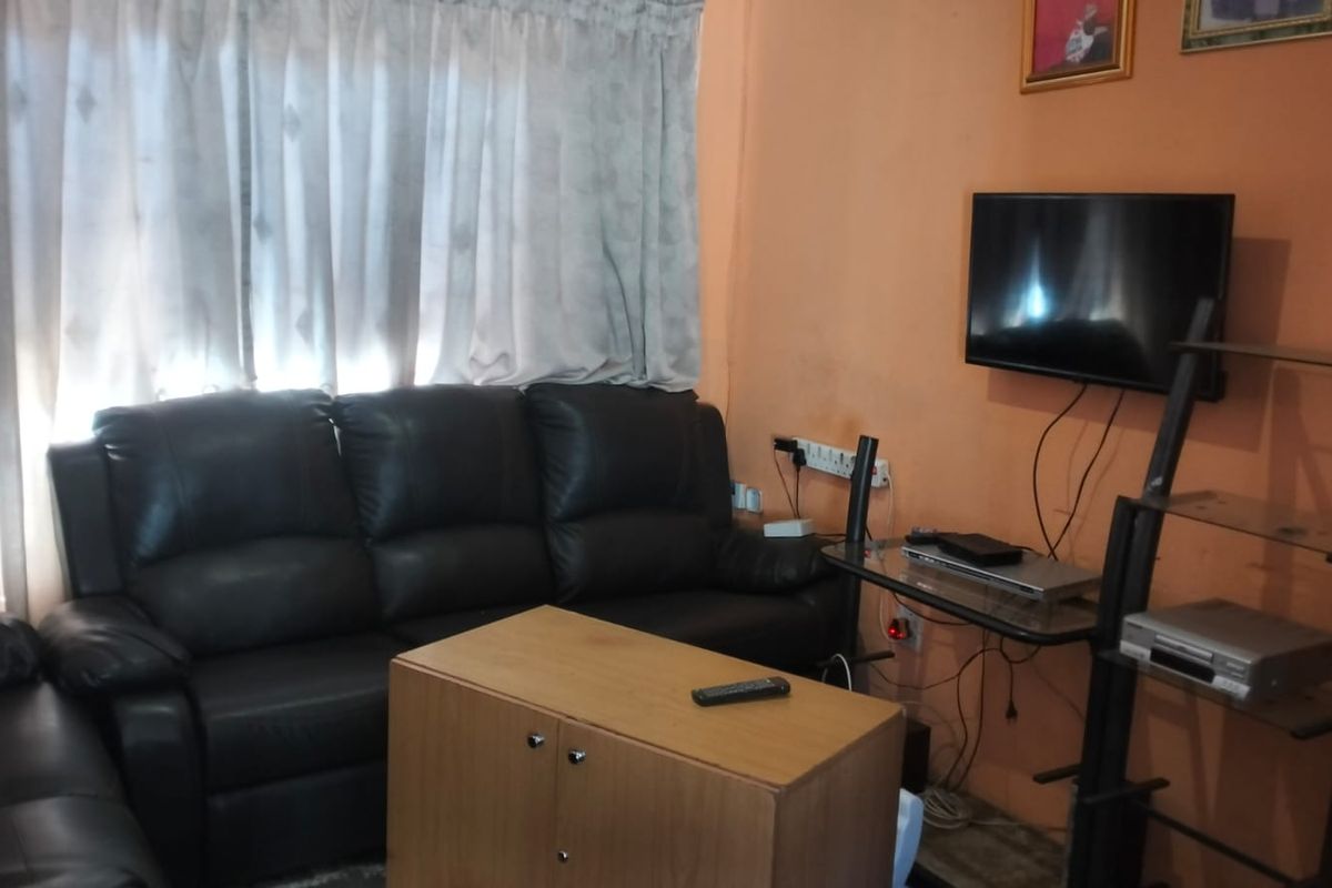 A living room area featuring wall-mounted television space and curtained windows, requiring cosmetic updates to the wall finishes and improved cable management.