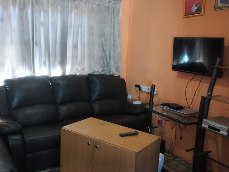 A living room area featuring wall-mounted television space and curtained windows, requiring cosmetic updates to the wall finishes and improved cable management.