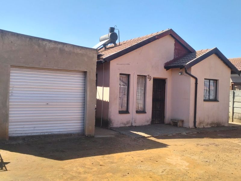 Front elevation of a single-story house featuring a detached garage, solar water heating system, and tiled roof structure.