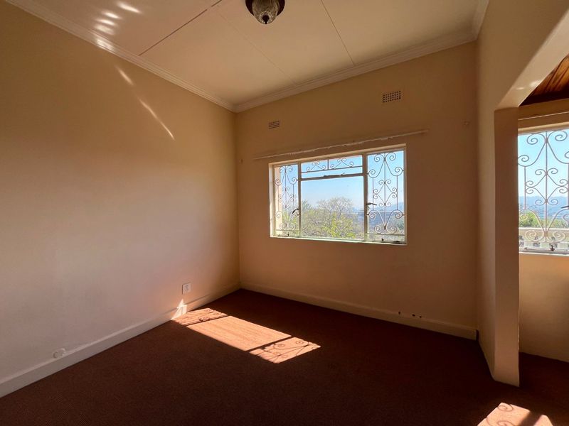 An empty bedroom featuring carpet flooring, security bars on the windows, and ceiling cornice detailing.