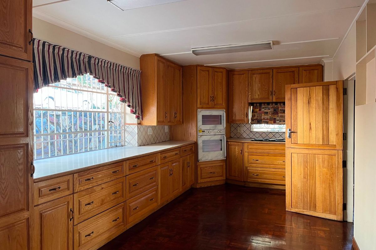 Spacious kitchen featuring extensive wooden cabinetry, built-in double oven, laminate countertops, and traditional parquet flooring.