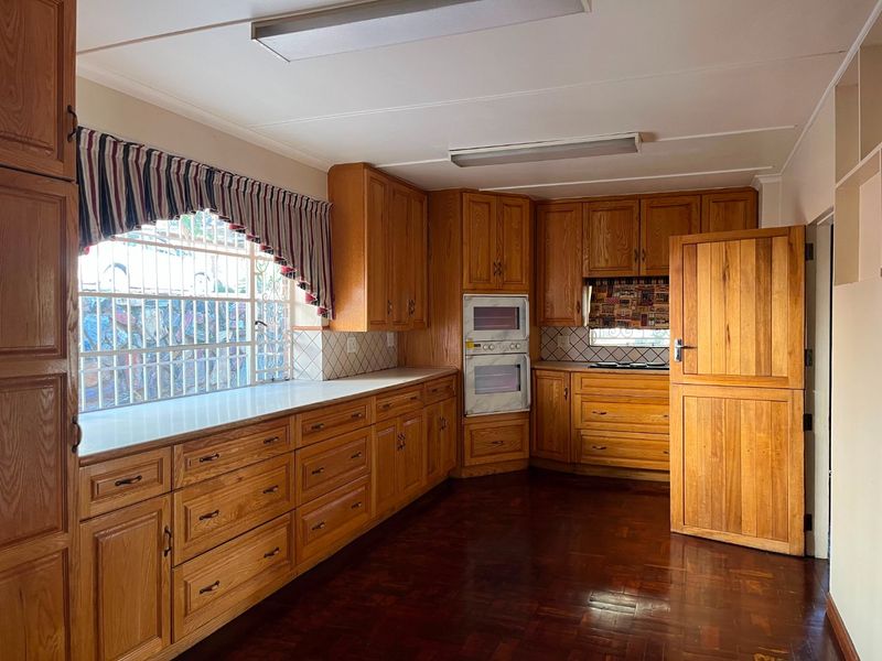 Spacious kitchen featuring extensive wooden cabinetry, built-in double oven, laminate countertops, and traditional parquet flooring.