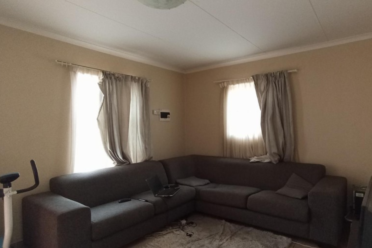 A living room featuring neutral wall paint, coving, and two windows with installed curtain rods.
