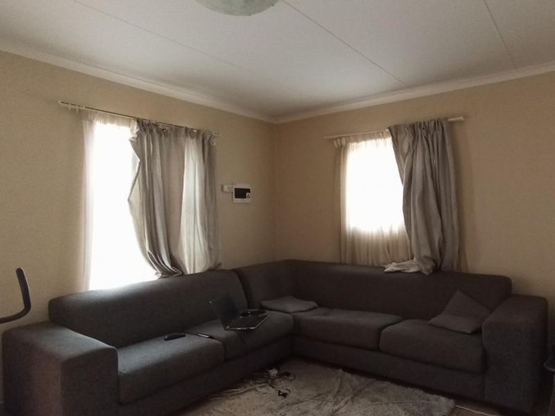A living room featuring neutral wall paint, coving, and two windows with installed curtain rods.