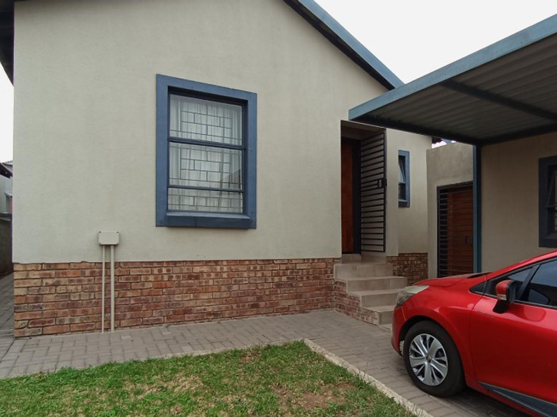 Front elevation of the house featuring a brick base, a covered carport, and paved driveway access.