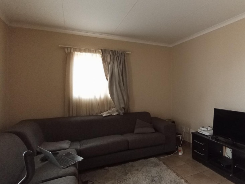A functional living room featuring tiled flooring and coved ceiling details, providing a neutral base for potential interior updates.