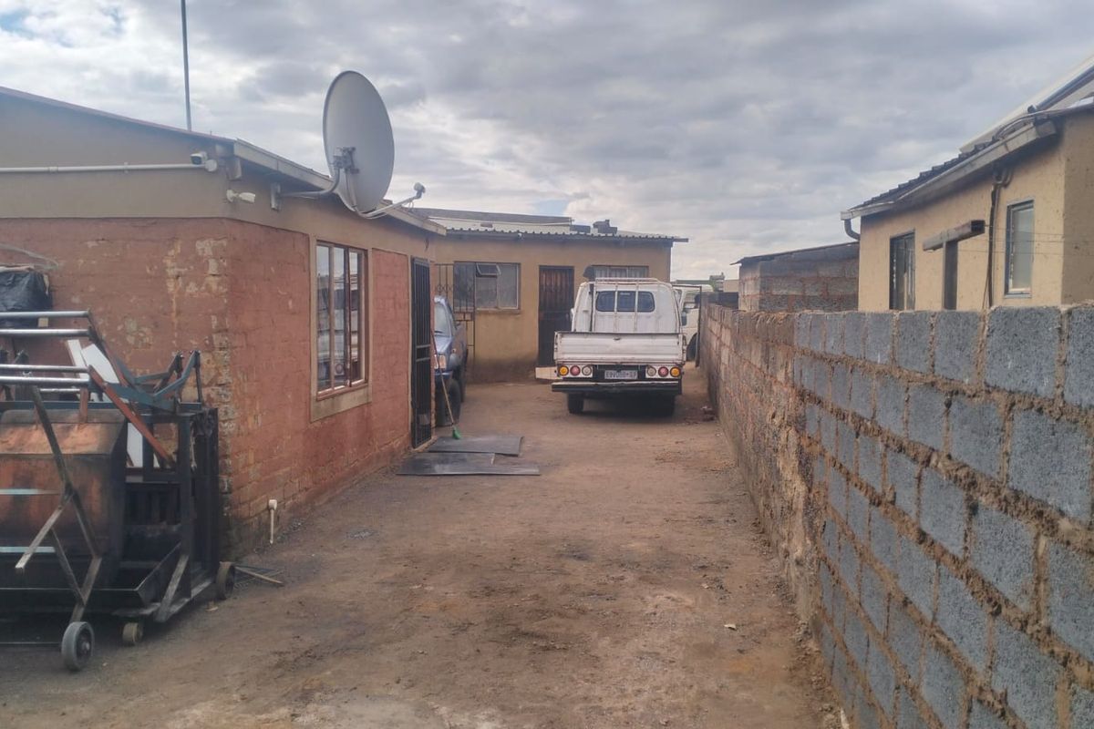 Rear exterior view of the property featuring a concrete block boundary wall and access to the side yard area.