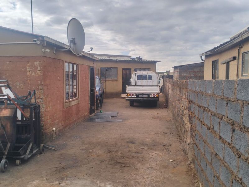 Rear exterior view of the property featuring a concrete block boundary wall and access to the side yard area.