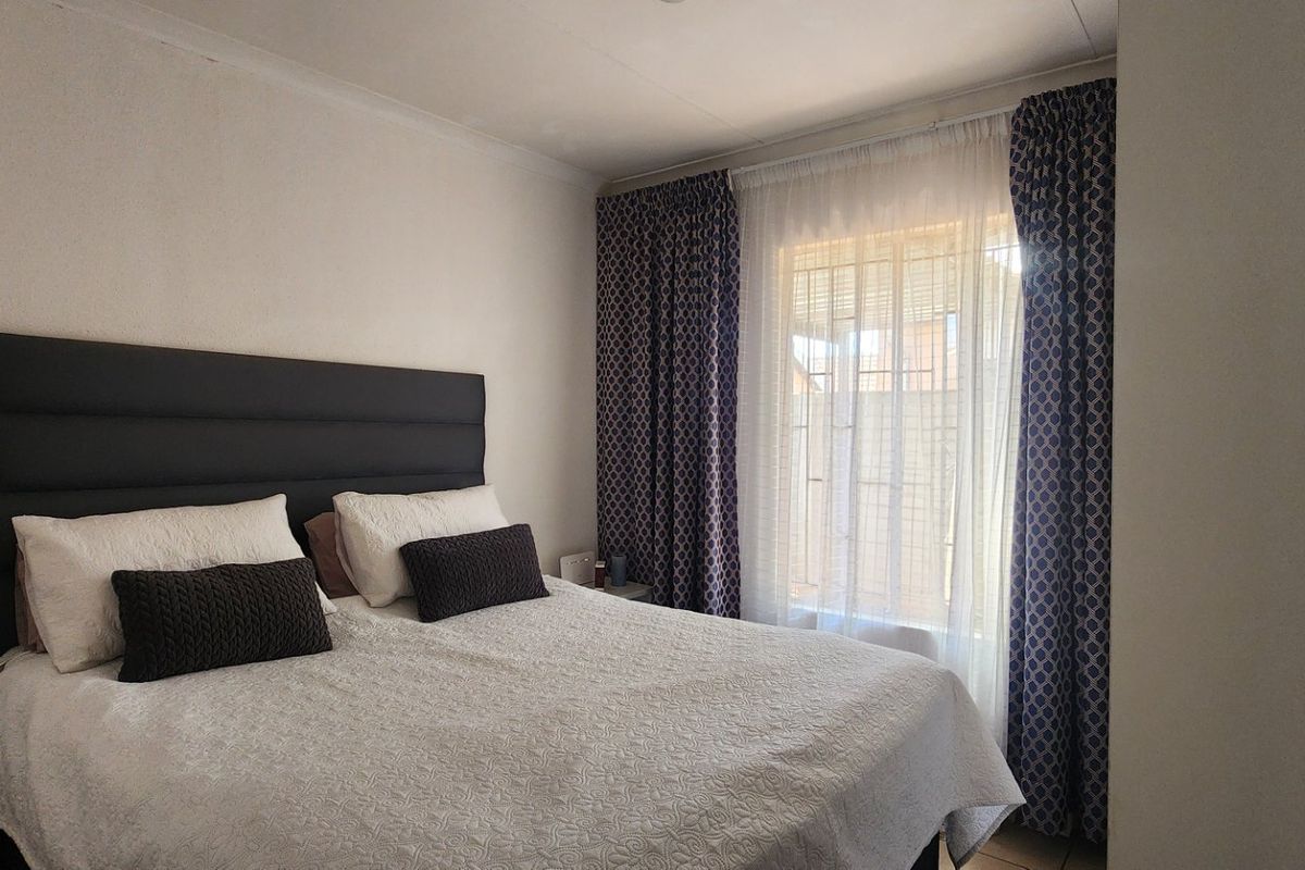 A functional bedroom featuring neutral walls, coving, and window treatments.