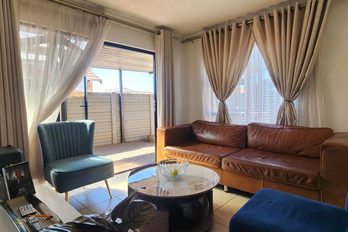 A bright living room featuring tiled flooring and a large sliding glass door that provides direct access to an outdoor patio area.