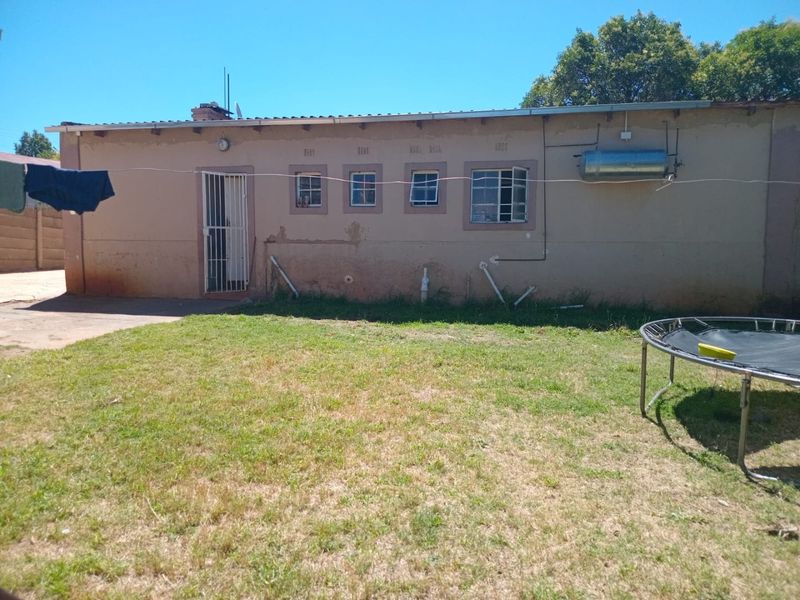 Rear view of the property showing the exterior wall, security gate, and window fixtures, requiring maintenance and cosmetic updates to the facade.