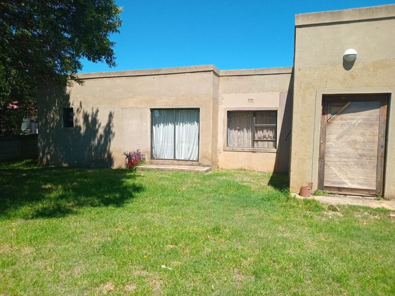 Rear view of the property featuring a concrete facade, sliding glass door, and a private garden area.