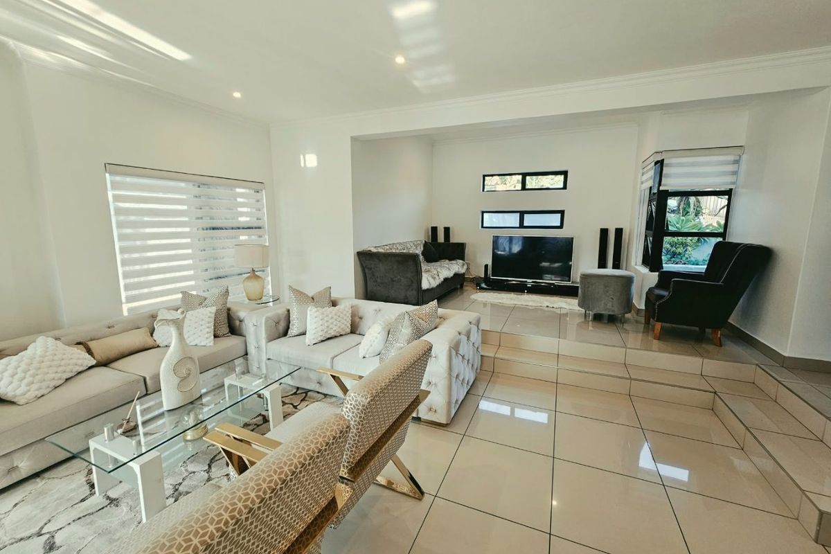 Spacious living room featuring polished porcelain floor tiles, a raised platform area, and modern recessed lighting with neutral wall finishes.