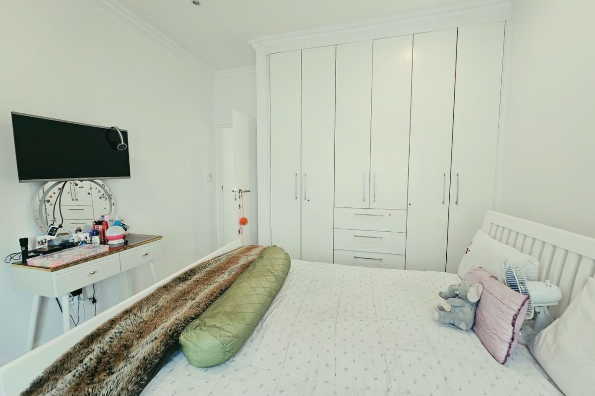 A well-maintained bedroom featuring ample built-in cupboard storage, recessed ceiling lighting, and decorative cornicing.