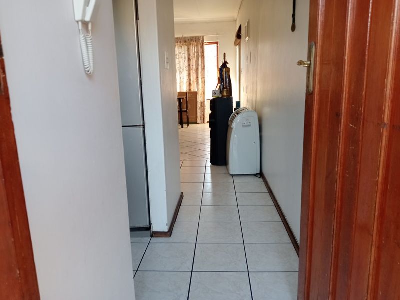 A functional hallway featuring tiled flooring and an intercom system, providing access to the main living areas of the apartment.
