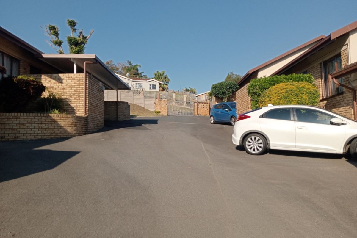 View of the apartment complex entrance featuring an asphalt driveway, face brick exterior walls, and a secure gated access point.