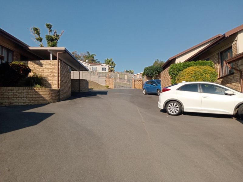 View of the apartment complex entrance featuring an asphalt driveway, face brick exterior walls, and a secure gated access point.