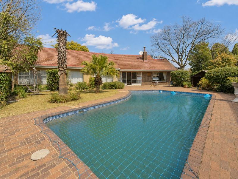 Spacious rear garden featuring a swimming pool with safety net, brick paved surround, and direct access to the main house via sliding doors.
