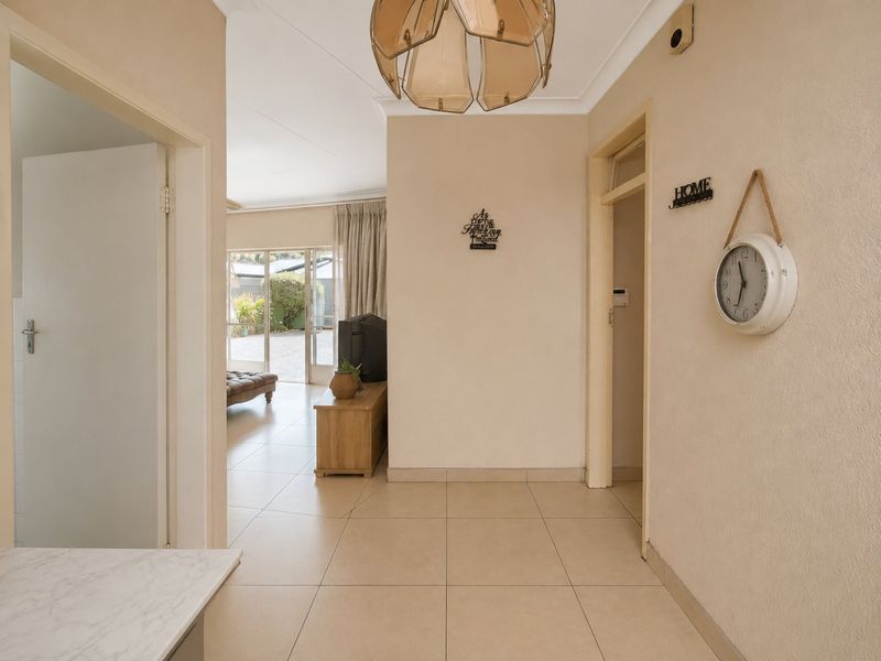 A bright, tiled hallway providing access to adjacent living areas, featuring neutral wall tones and a central pendant light fixture.