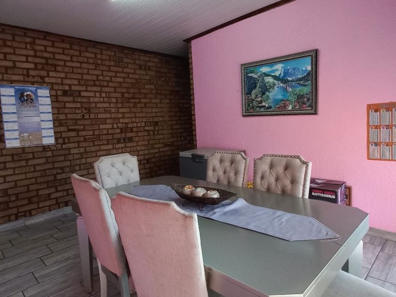 Dining room featuring exposed brick walls, tiled flooring, and an arched entryway leading to the kitchen area.