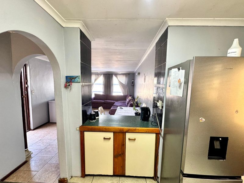 Open plan kitchen area featuring a breakfast counter, tiled splashbacks, and an arched entryway leading to the adjacent living space.