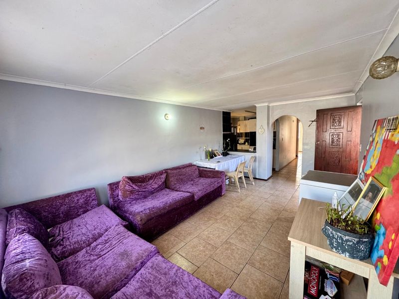 Open plan living area featuring tiled flooring and an arched entryway leading to the kitchen and hallway.