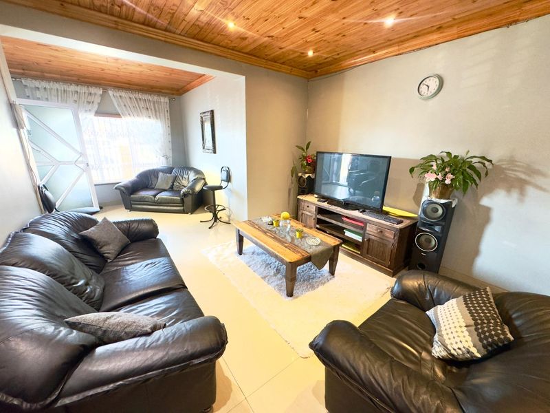 Spacious living room featuring a warm timber tongue and groove ceiling, recessed downlights, and neutral tiled flooring throughout.