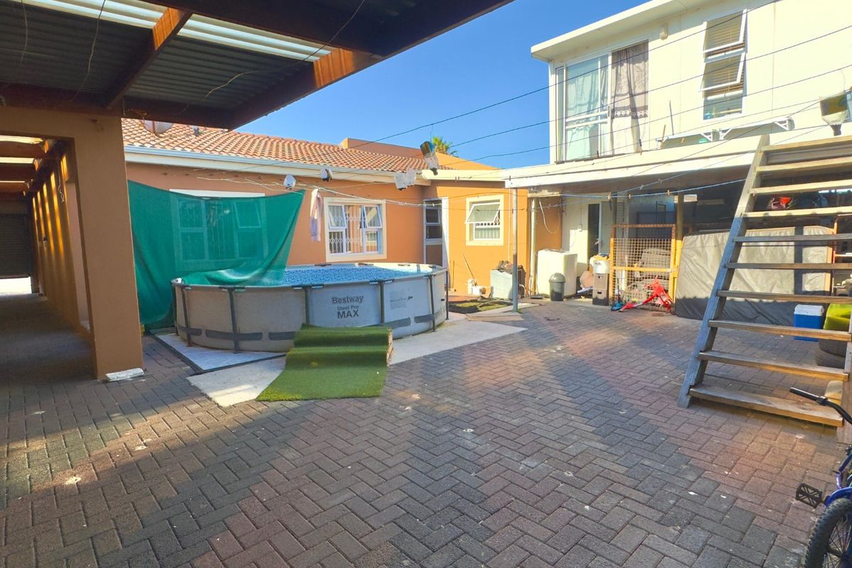 Rear courtyard area featuring paved flooring, a covered patio section, and an external staircase leading to the upper level of the property.