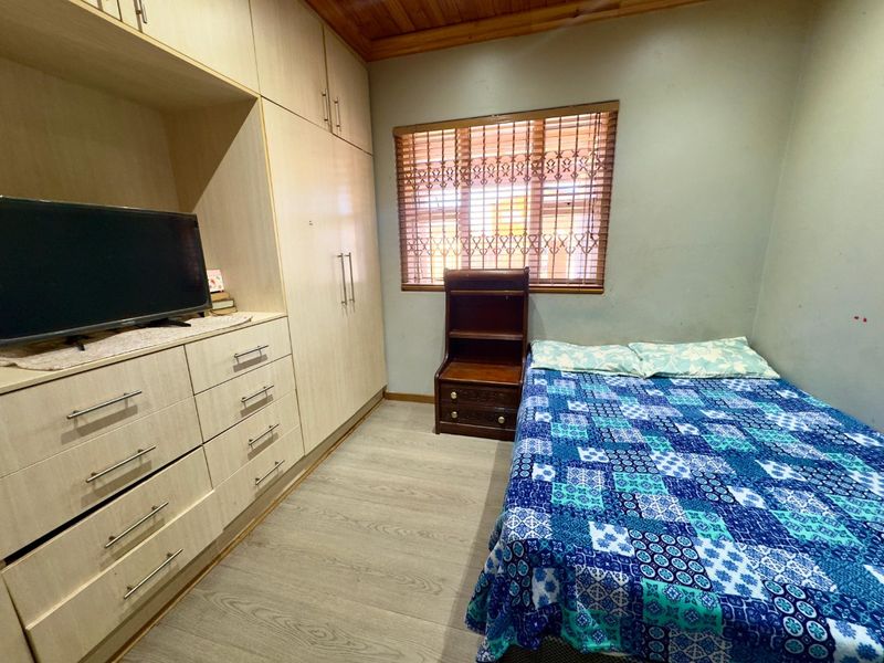 A bedroom featuring built-in cupboards, laminate flooring, and a timber ceiling, providing functional storage and a neutral base for interior updates.
