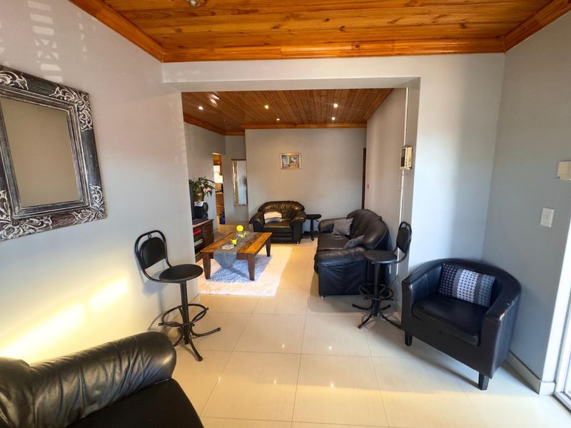 Open plan living area featuring ceramic floor tiles and a timber tongue and groove ceiling with recessed downlights.
