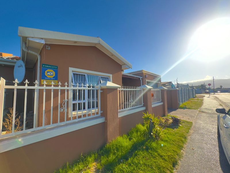 Front exterior view of the house featuring a perimeter wall with security fencing, security bars on windows, and a satellite dish installation.