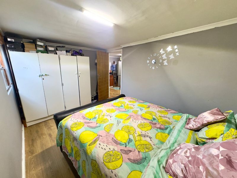 A functional bedroom featuring laminate flooring, a built-in wardrobe, and cove cornice detailing, offering a practical living space.
