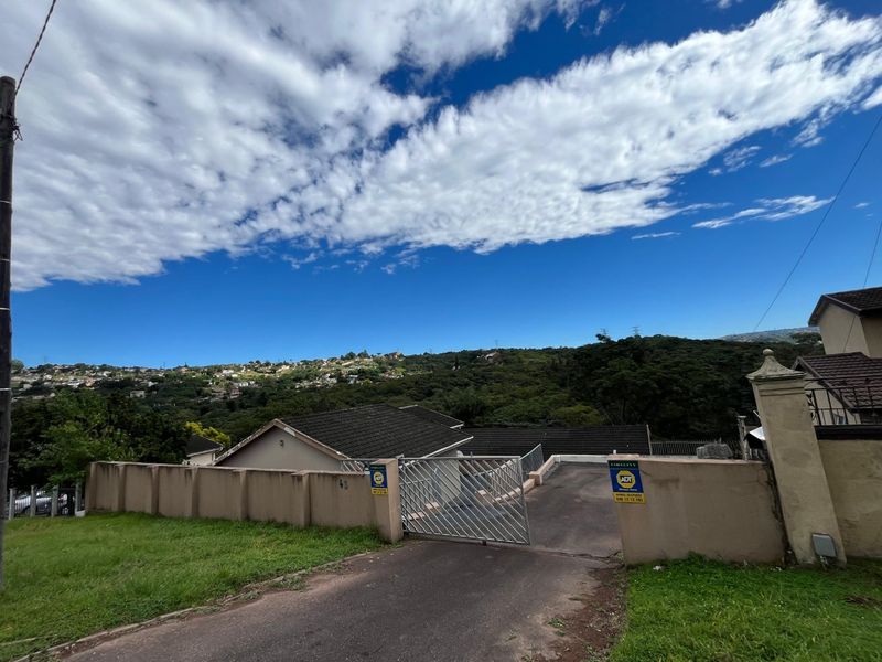 Front exterior view of the property featuring a gated driveway entrance, perimeter wall, and tiled roof structure.