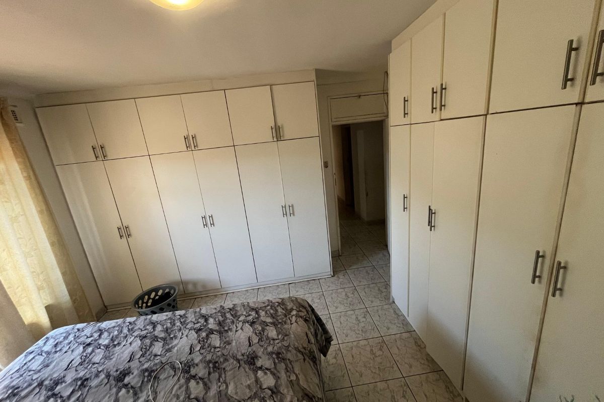 Bedroom featuring extensive floor-to-ceiling built-in cupboards and tiled flooring, offering ample storage space.