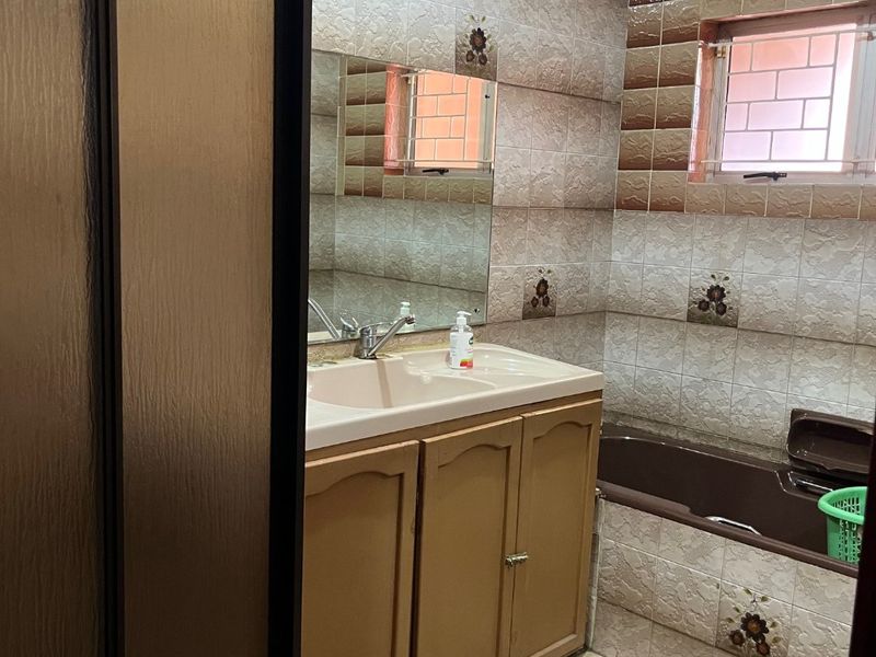 A dated bathroom featuring a vanity cabinet with integrated basin, a bathtub, and decorative wall tiling throughout.