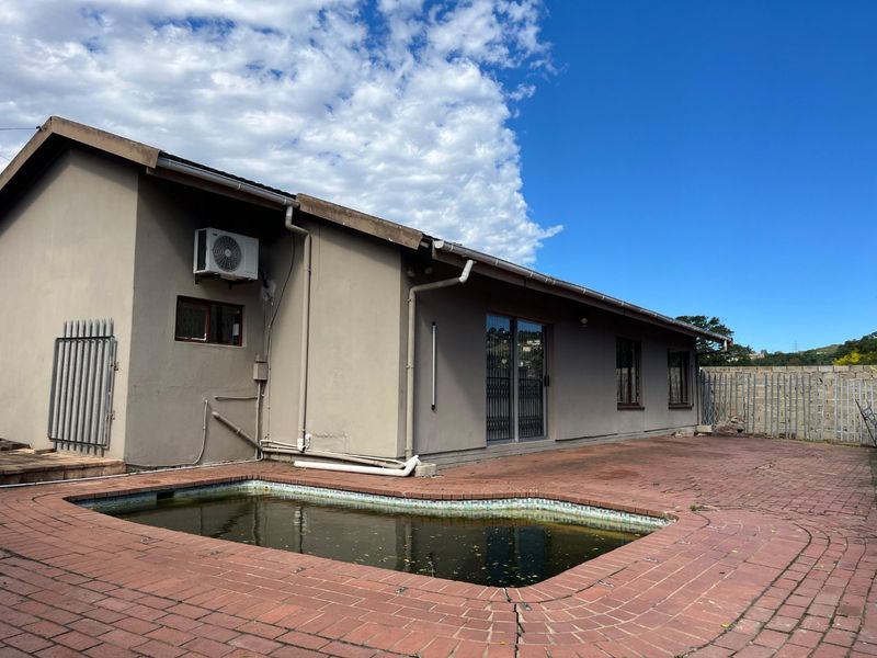 Rear exterior view featuring a swimming pool with brick paved surround, sliding door access, and wall-mounted air conditioning unit.