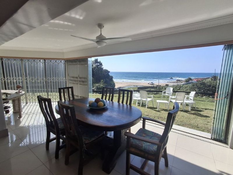 Covered patio area featuring tiled flooring, ceiling fan, and expansive sliding glass doors opening to a scenic ocean view.