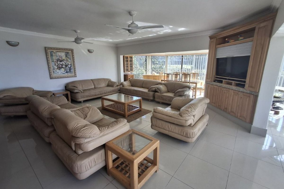 Spacious living room featuring tiled flooring, dual ceiling fans, and extensive built-in wooden cabinetry for storage and media display.