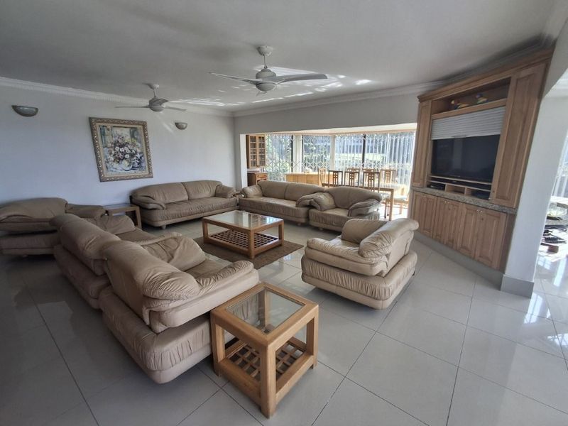 Spacious living room featuring tiled flooring, dual ceiling fans, and extensive built-in wooden cabinetry for storage and media display.