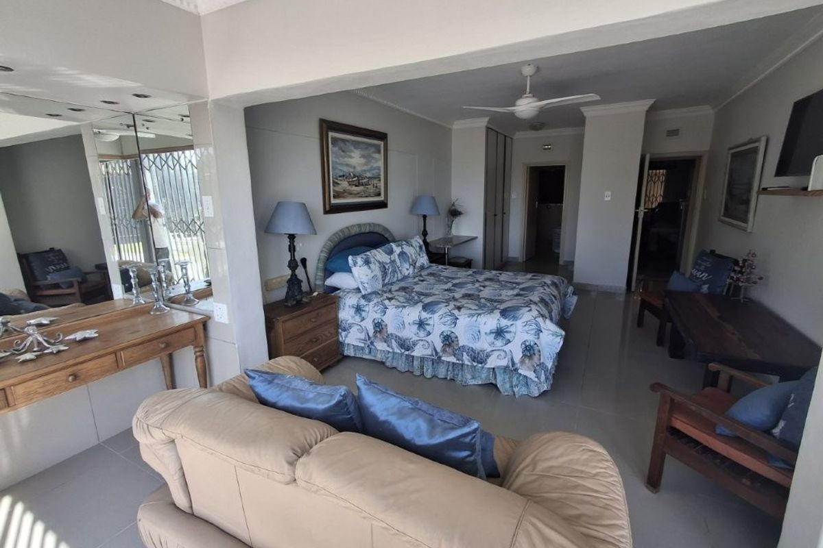 Spacious bedroom featuring tiled flooring, built-in cupboards, and a ceiling fan, offering a functional layout with integrated storage and neutral finishes.